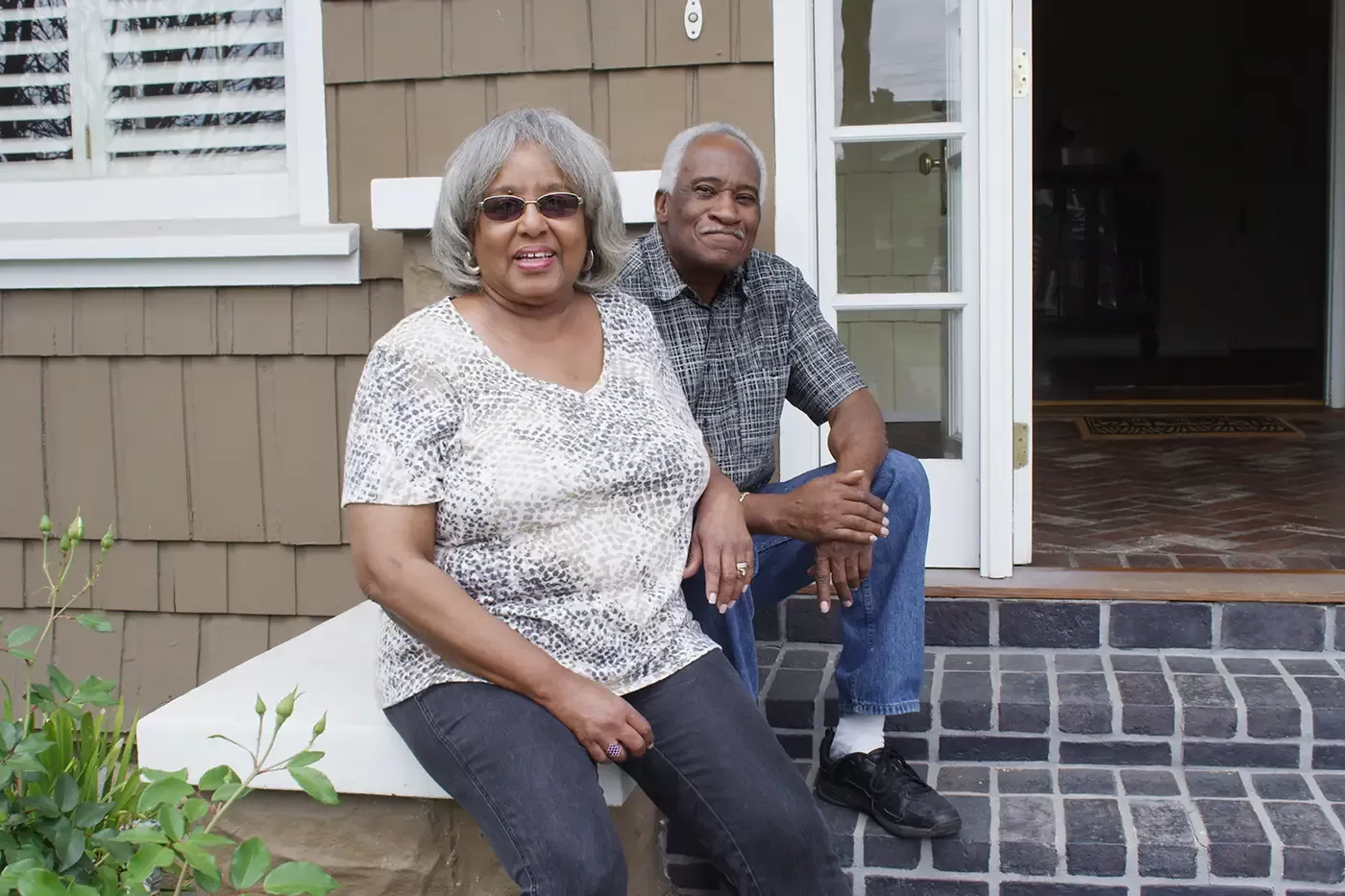 An older couple sitting outside their appartment