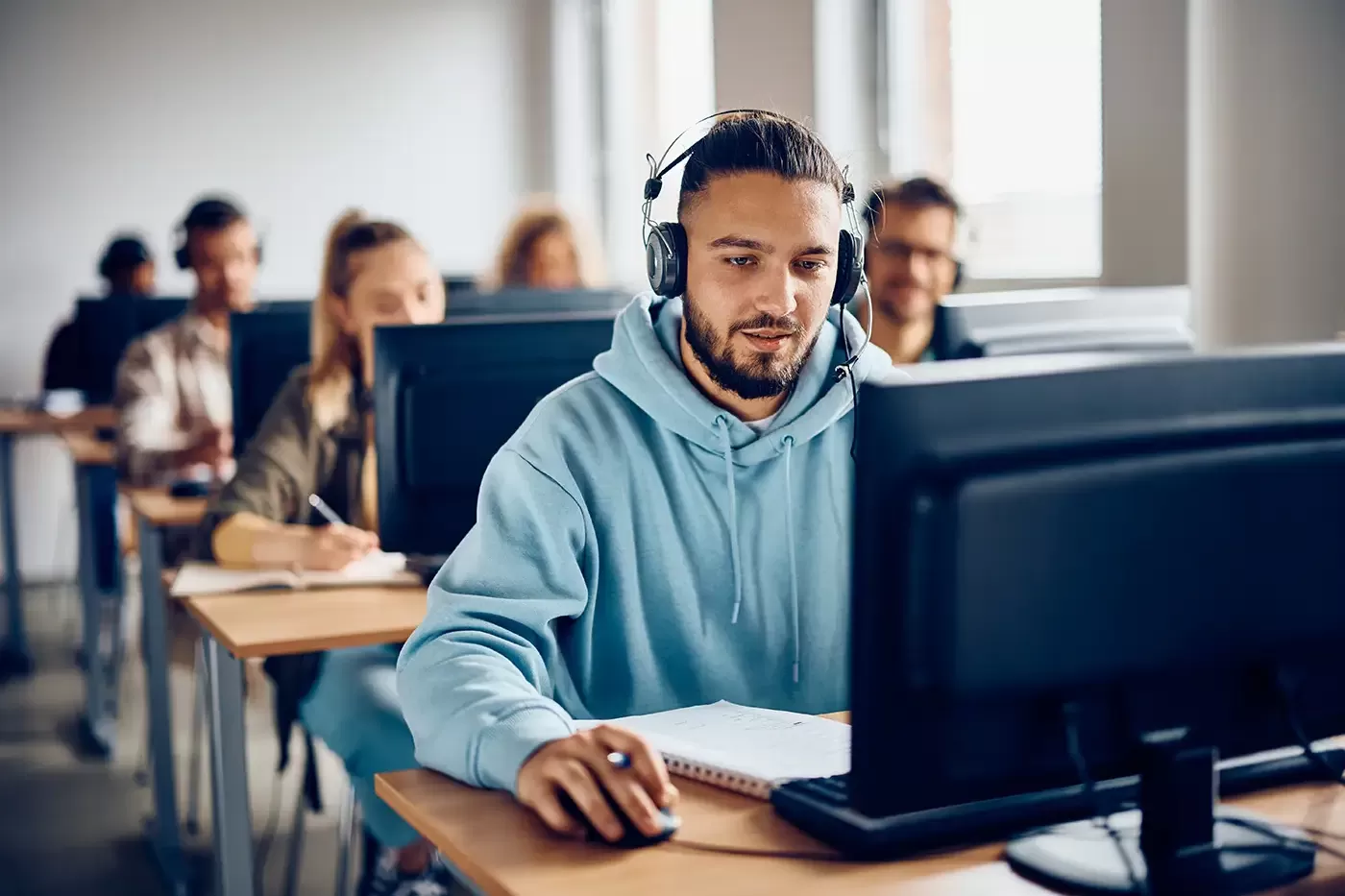 Young adult e-learning on computer in a classroom.